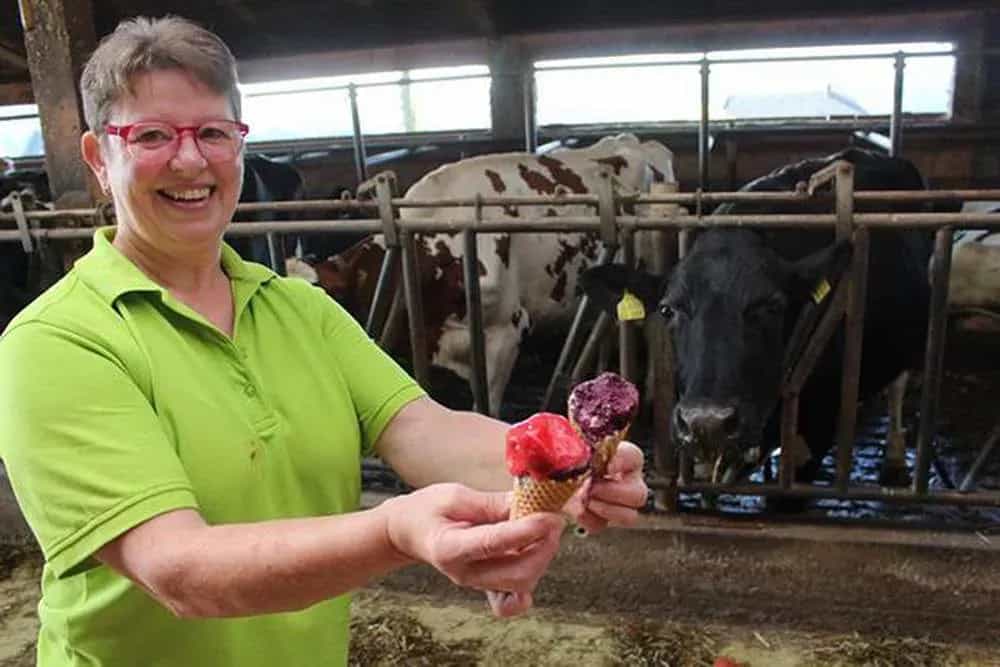 A dairy farmer holding ice creams in her dairy farm mirrored